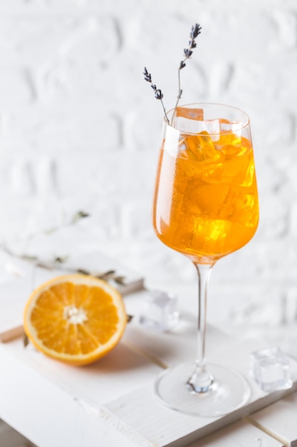 Cóctel Aperol Spritz en vidrio sobre fondo blanco.