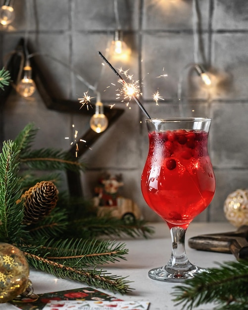 Cóctel de arándanos y bengala ardiente en luces de guirnaldas. concepto de feliz navidad