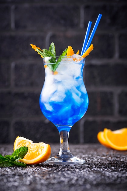 Cóctel azul con hielo y naranja.