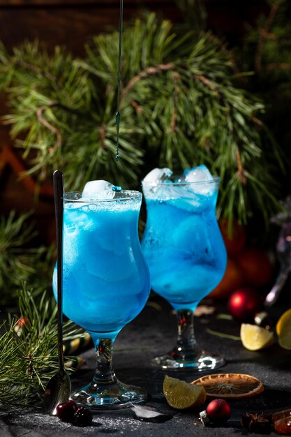 Cóctel azul en un vaso alto con hielo y rodajas de limón sobre un fondo de madera