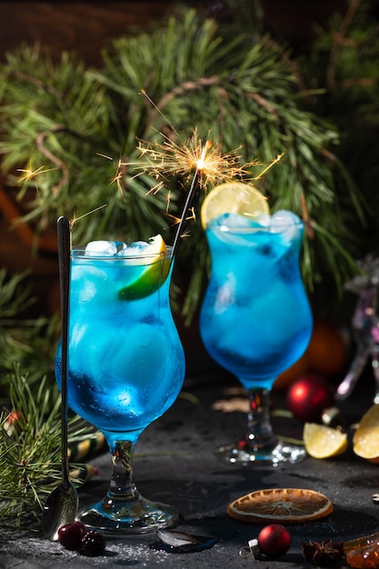 Cóctel azul en un vaso alto con hielo y rodajas de limón sobre un fondo de madera