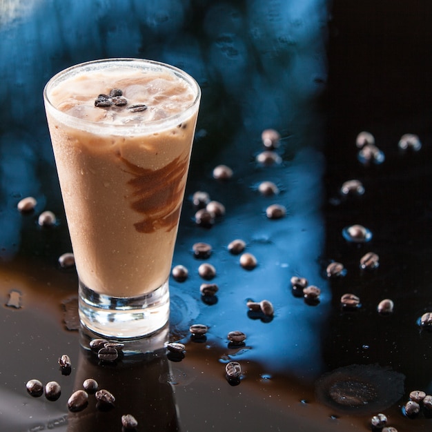 Cóctel de bebida de café y chocolate con granos de café sobre fondo húmedo