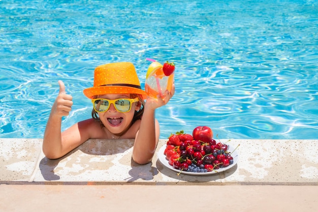Cóctel de bebida infantil Niño de verano junto a la piscina comiendo fruta y bebiendo cóctel de limonada Niños de verano
