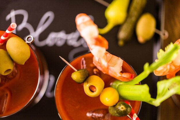 Foto cóctel bloody mary aderezado con aceitunas, encurtidos y camarones cóctel.