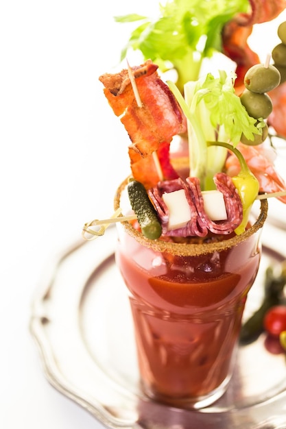 Cóctel Bloody Mary adornado con palitos de apio, aceitunas y tiras de tocino.