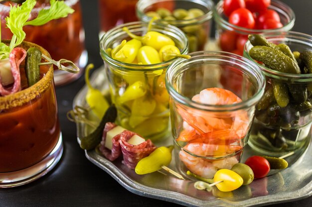 Cóctel Bloody Mary adornado con palitos de apio, aceitunas y tiras de tocino.