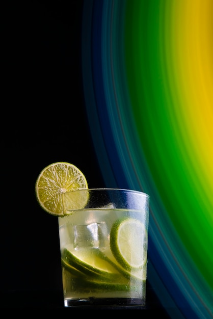 Cóctel brasileño llamado Caipirinha. Con limón, hielo y cachaÃ§a sobre un fondo oscuro con luces de colores. Copia espacio