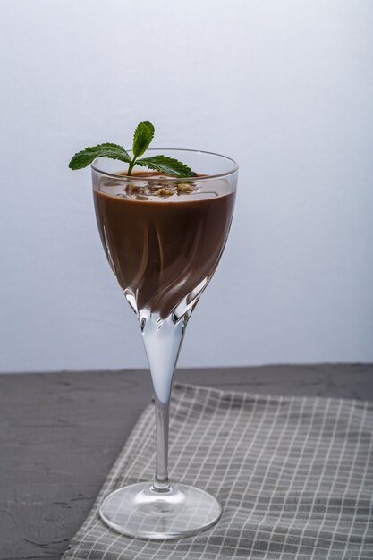 Cóctel de chocolate con nueces y menta en un vaso sobre una superficie negra