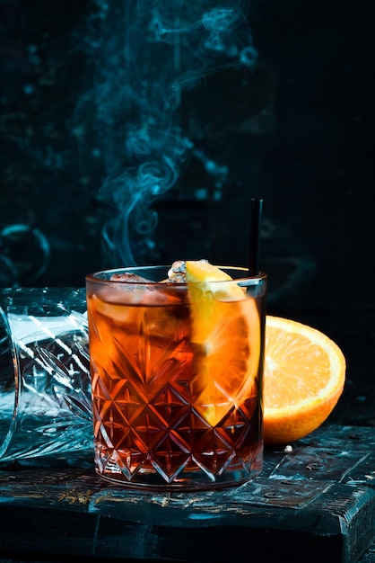 Cóctel clásico Negroni en un vaso retro con hielo y cáscara de naranja sobre un fondo negro Menú del bar