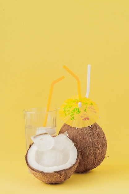 Cóctel de coco fresco con una pajita sobre fondo amarillo
