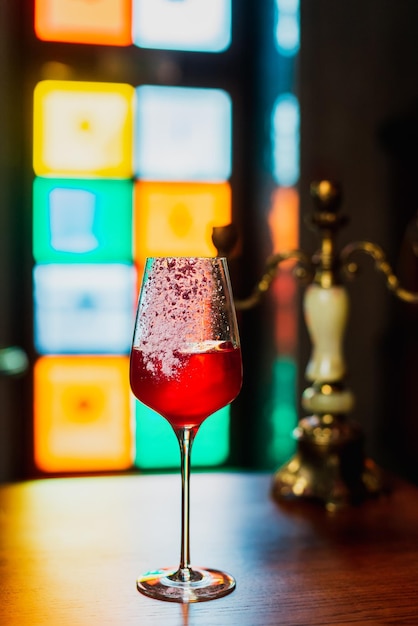 Un cóctel en una copa de vino con un cubo de hielo.