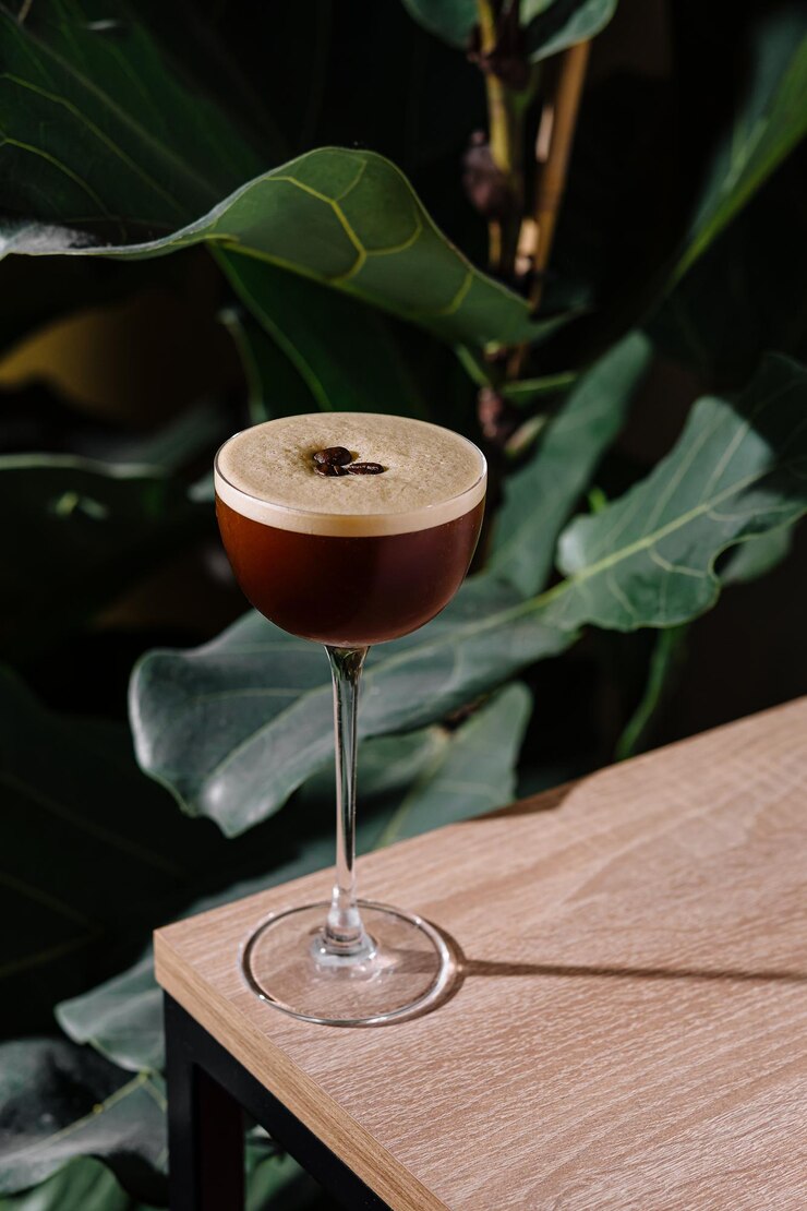Un cóctel de espresso martini de pie en una mesa de madera en una atmósfera tropical