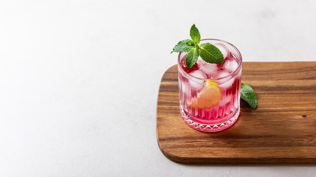 Foto cóctel de frambuesa con hielo en un vaso sobre un fondo claro