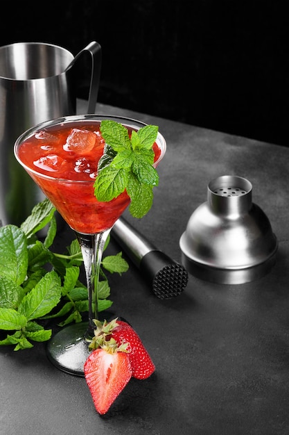 Cóctel de fresa de verano frío mojito margarita daiquiri en una copa de martini sobre fondo oscuro con juego de barman