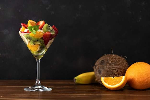Cóctel de frutas en copa de martini sobre mesa de madera.