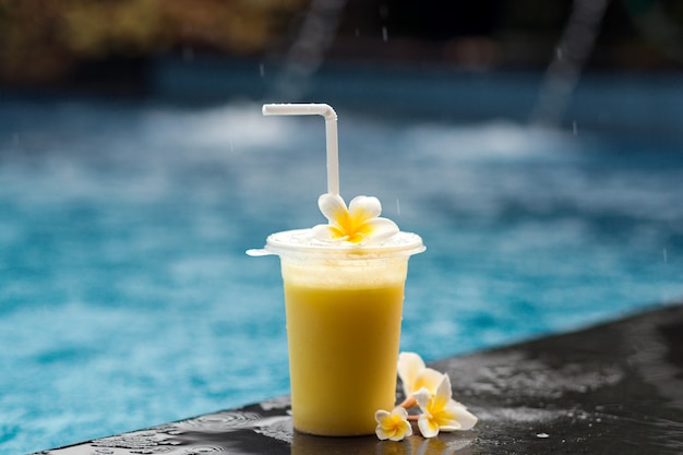 Cóctel de frutas y flor de frangipani junto a la piscina