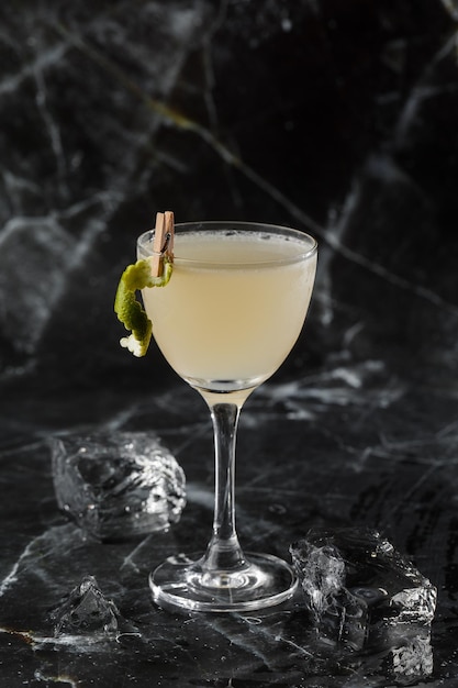 Cóctel Gimlet Kamikaze en copa de martini con hielo sobre fondo de mármol negro Cócteles alcohólicos cítricos