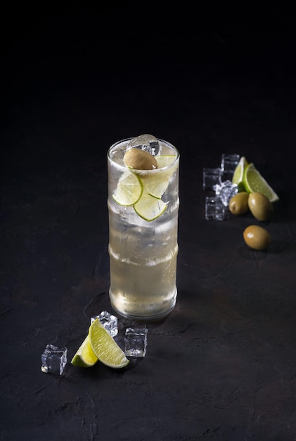 Cóctel con Gin Perejil, limón, oliva y hielo picado sobre un fondo oscuro Tarjeta de cóctel