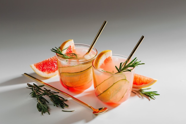 Cóctel de gin de pomelo y pepino en elegantes vasos sobre fondo blanco con sombras