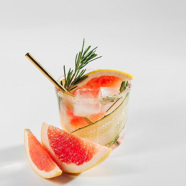 Cóctel de ginebra de pomelo y pepino en vasos elegantes sobre fondo blanco.