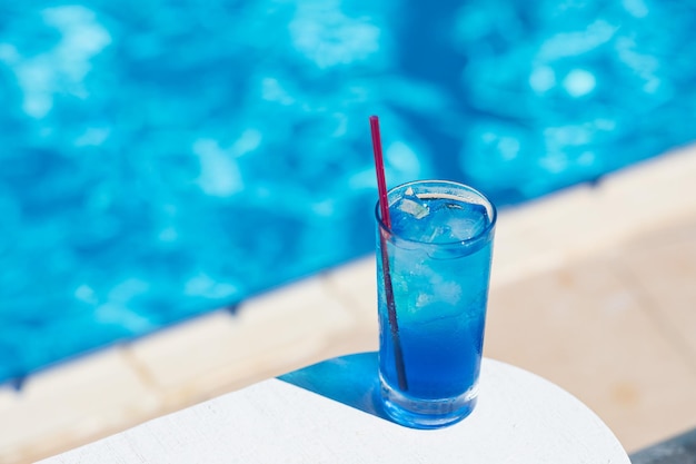 Cóctel laguna azul con hielo cerca de la piscina en un día soleado Refrescos de verano