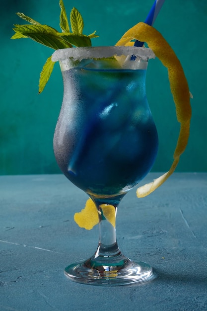 Cóctel laguna azul con licor de curacao azul vodka jugo de limón y soda decorado con rodaja de limón y hojas de menta