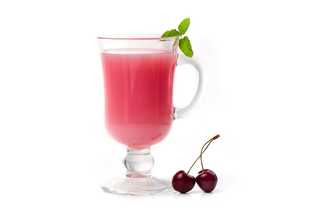 Cóctel de leche con cereza en un vaso transparente y frutos rojos sobre un fondo claro.