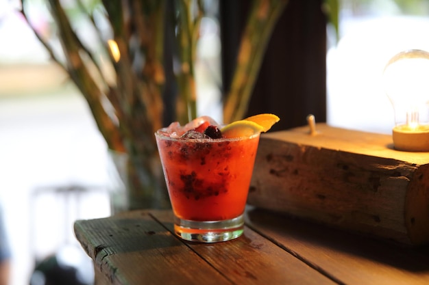 Cóctel Mai Tai con frutos de cereza naranja sobre fondo de madera