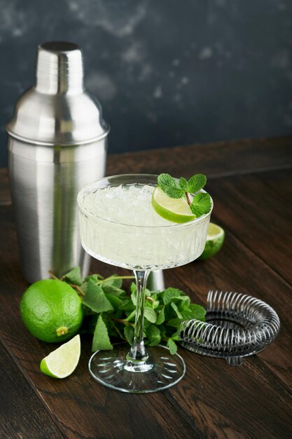 Foto cóctel de margarita con menta de tequila de lima y hielo en una mesa oscura con un increíble espacio de copia de luz de fondo concepto clásico de tarjeta o mostrador de margarita o daiquiry cocktail bar enfoque selectivo o suave