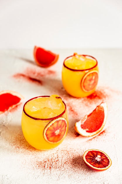 Cóctel de margarita de naranja sanguina en un vaso antiguo con pimentón ahumado en el borde, pomelo rosado.