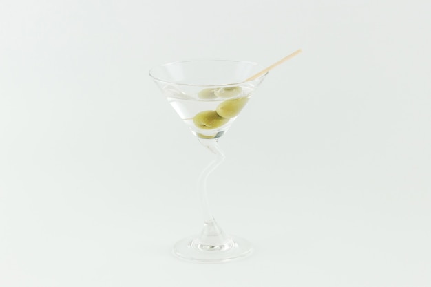 Cóctel Martini con aceitunas verdes sobre fondo blanco.