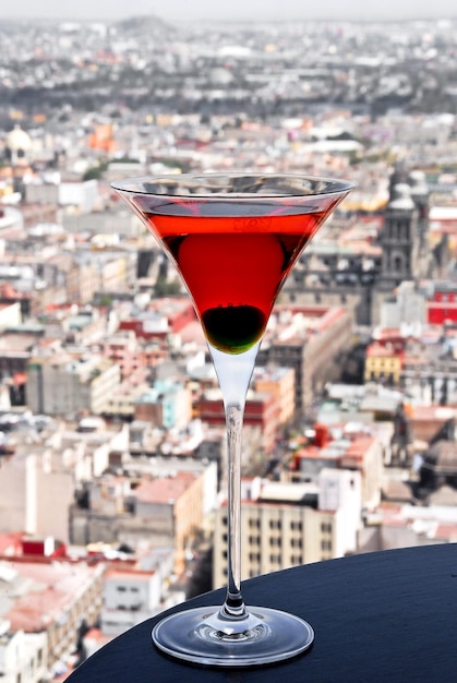 cóctel Martini Cosmopolitan, con cereza, en el fondo vista panorámica de la ciudad, bebidas