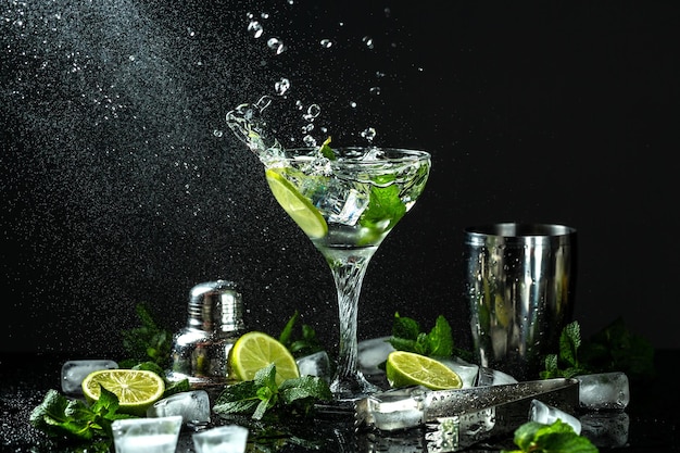 Cóctel Mojito clásico Ingredientes limón menta azúcar hielo con salpicaduras sobre fondo oscuro Congelar gotas de movimiento en salpicaduras de líquido bebida nacional cubana