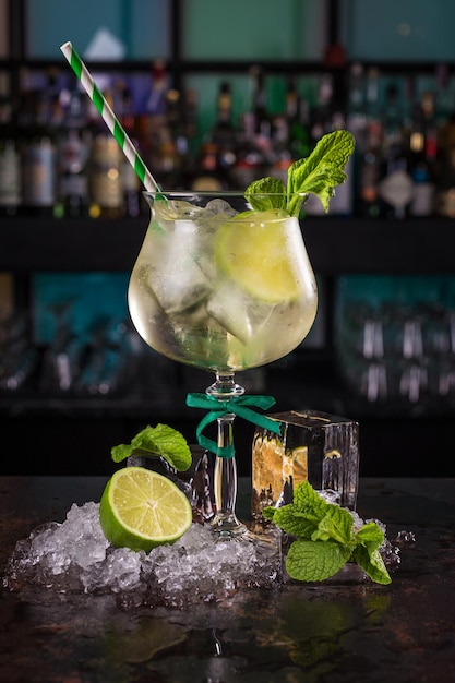 Cóctel mojito con lima limón y menta y cubitos de hielo sobre fondo negro