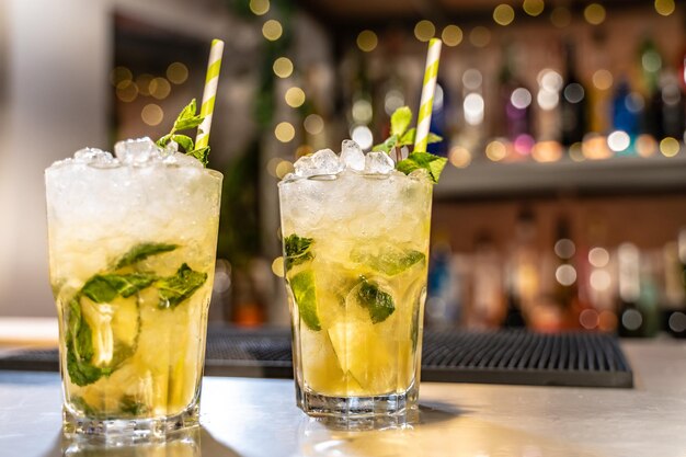 Cóctel de mojito en el mostrador de la barra con limones, limas y especies con espacio de copia para el texto