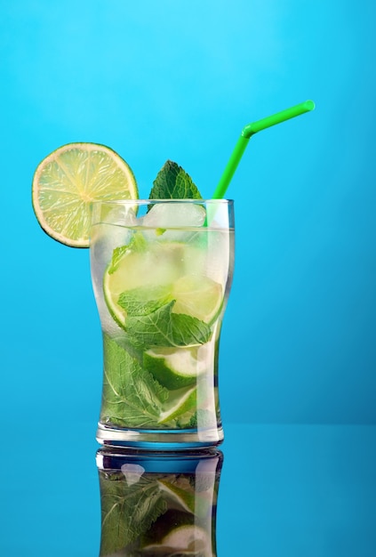 Cóctel mojito sobre fondo azul.