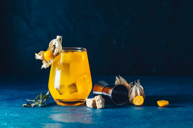 Cóctel de naranja amarillo con mandarina y romero en vaso con gotas de agua decoradas