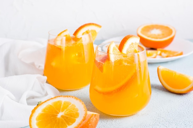 Cóctel de naranja carbonatada con seltzer duro con hielo en vasos y rodajas de naranja sobre la mesa Bebida casera