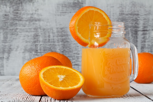 Cóctel de naranja en un frasco de vidrio sobre un fondo de madera