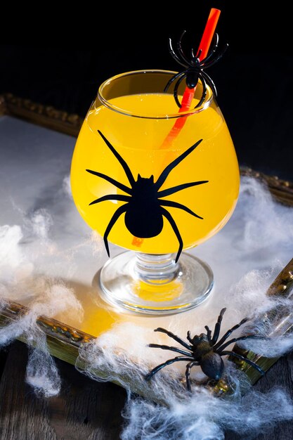 Cóctel de naranja de Halloween en vaso con araña