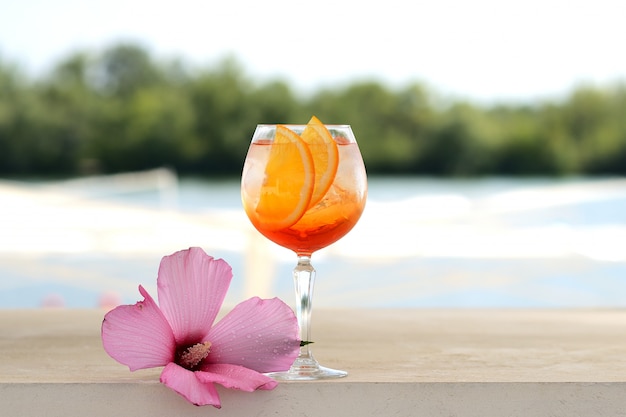Cóctel con naranja y hielo en un vaso de vidrio. Con decoración floral