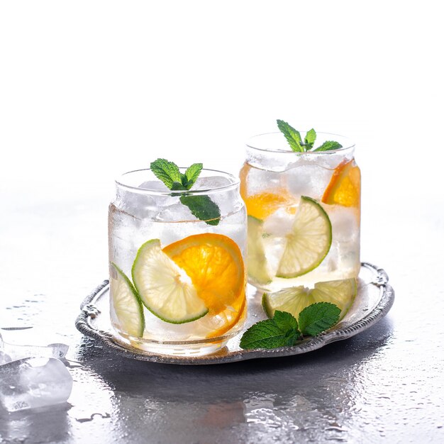 Cóctel de naranja con menta y lima. Bebida refrescante fría o bebida con hielo. Bebidas frías con hielo y menta.