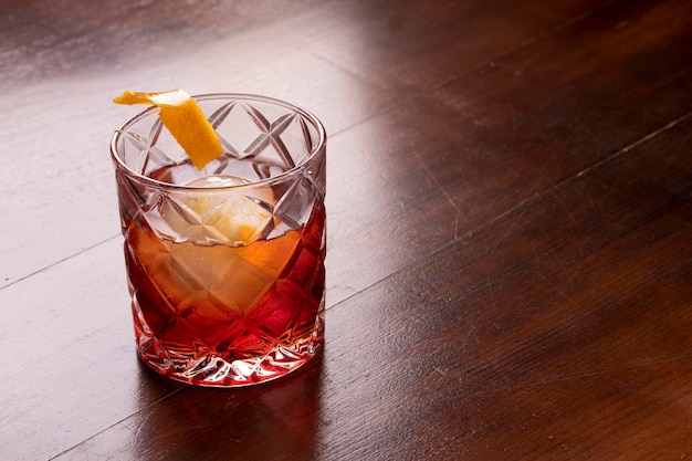 Cóctel Negroni de cerca en formato vertical de mesa de madera