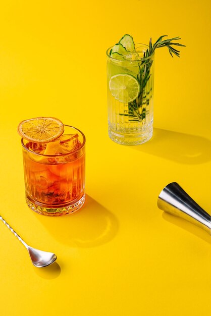 Cóctel Negroni y cóctel mojito sobre un fondo amarillo