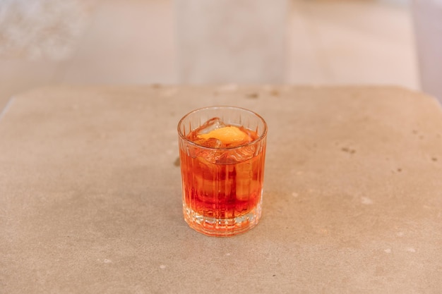 Cóctel de Negroni con hielo en vidrio transparente en la mesa del restaurante aislado en el fondo