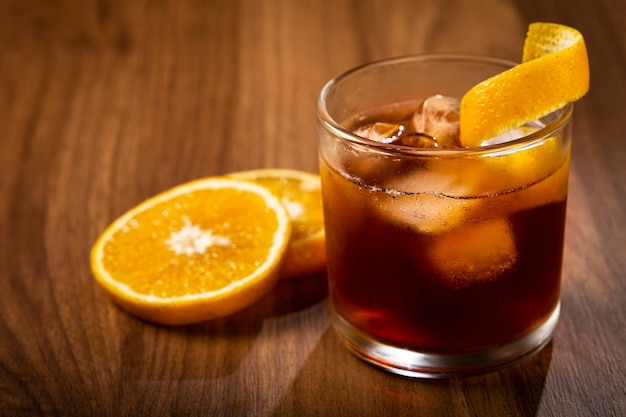 Cóctel Negroni con naranja sobre fondo de madera