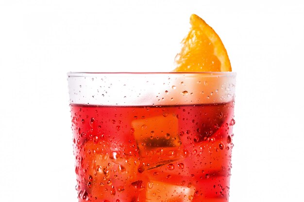 Foto cóctel negroni con trozo de naranja en vidrio aislado en blanco cerrar