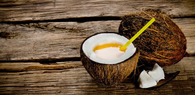 Cóctel de piña colada. Un cóctel fresco en copa de coco sobre mesa de madera. Espacio libre para texto.