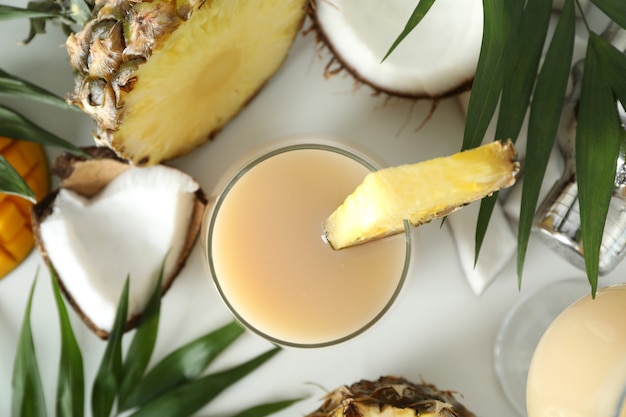 Cóctel de piña colada e ingredientes sobre fondo blanco.