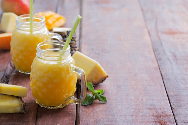 Cóctel de piña fresca con frutas sobre una mesa rústica de madera